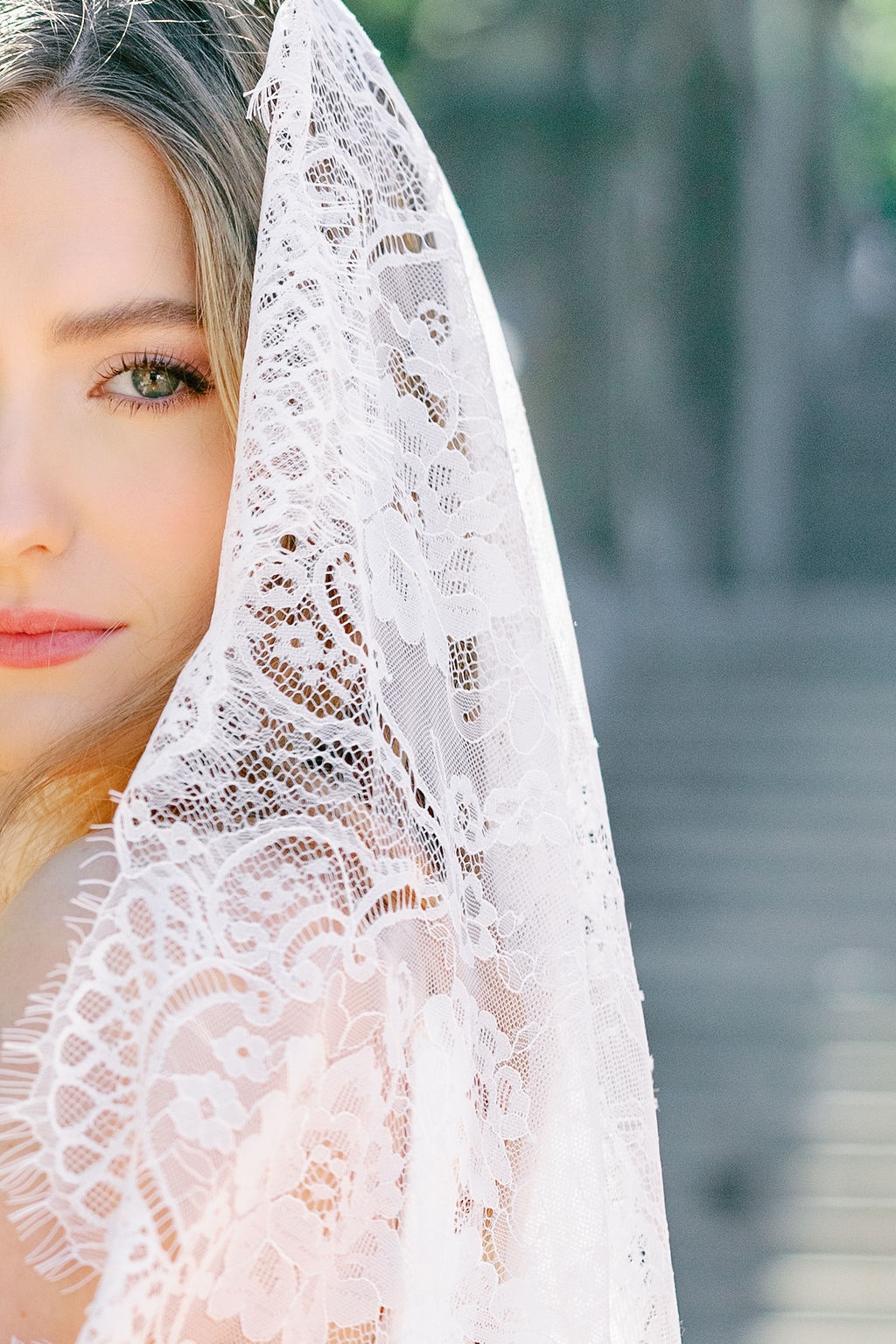 Bride wearing a delicate lace veil, photographed in soft natural light