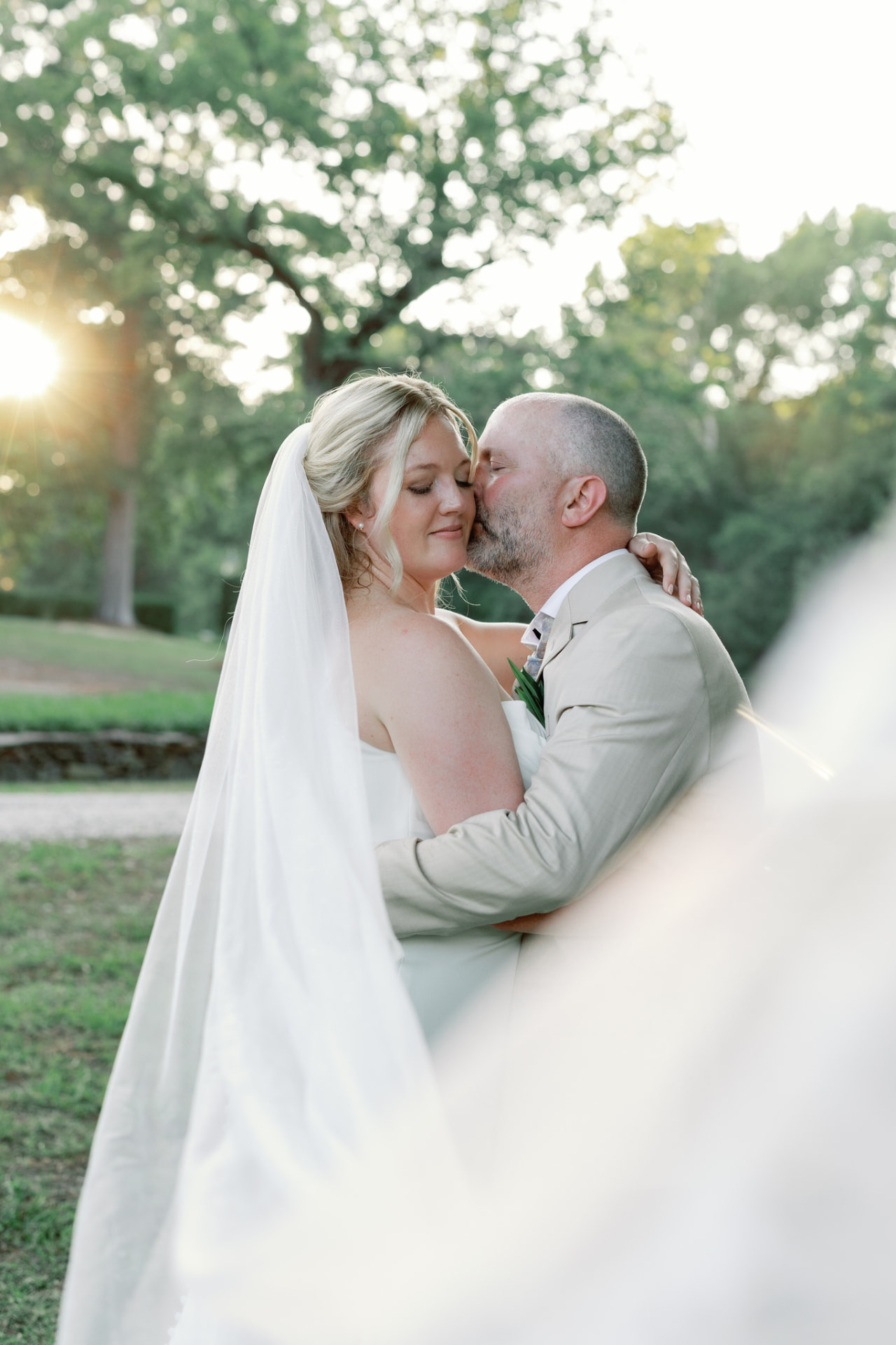Bride and groom embracing at golden hour, cathedral veil trailing